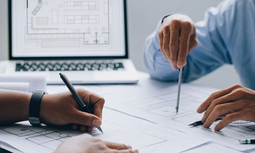 architect drawing on a blueprint on architectural project at the construction site at office desk in the office.Architectural and engineering concept.