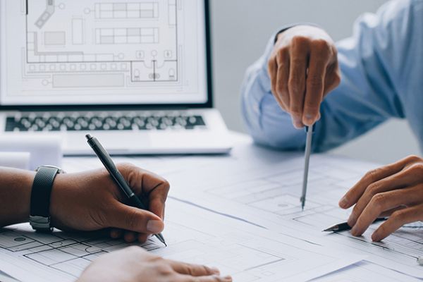 architect drawing on a blueprint on architectural project at the construction site at office desk in the office.Architectural and engineering concept.